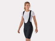 Three-quarter angled studio view of female model facing left in black Trek Solstice women's bib shorts, highlighting how the fitted shape and fabric drape in a riding posture