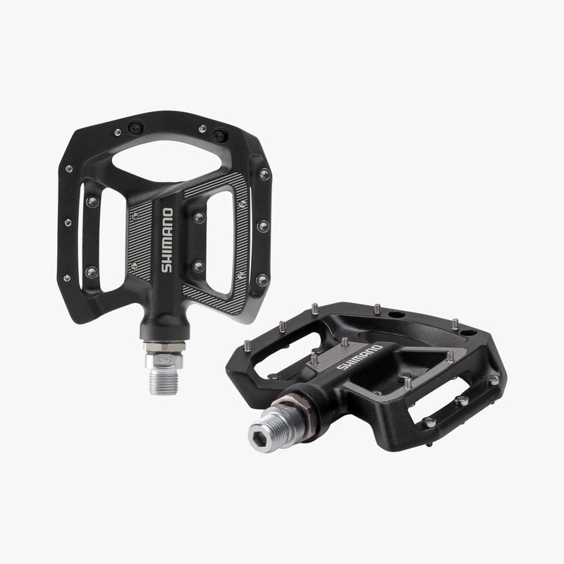 Two black Shimano bicycle pedals on a white background