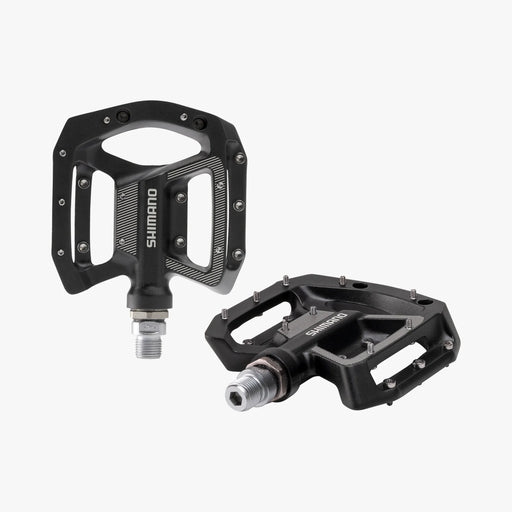 Two black Shimano bicycle pedals on a white background
