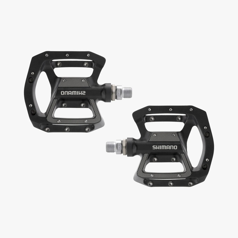 Two black Shimano bicycle pedals on a white background