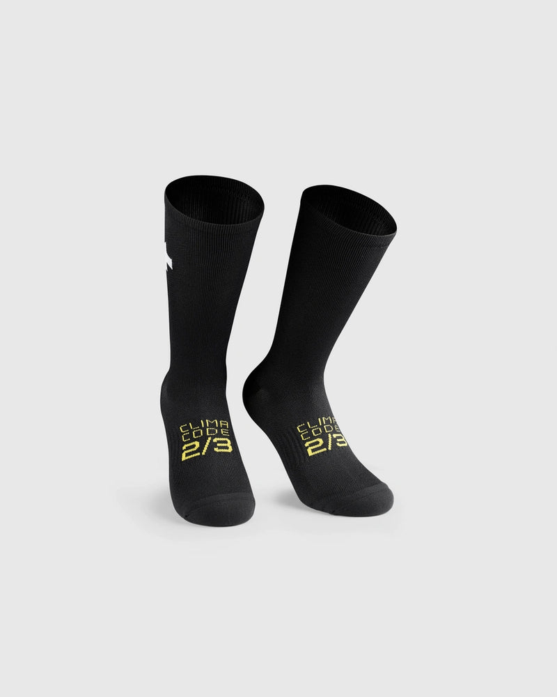 Black socks with yellow text and white Assos logo, on a light gray background