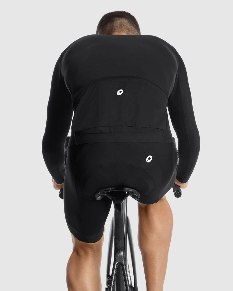 Person wearing a black cycling outfit with a [pocet panel, visible brand logo on a white background