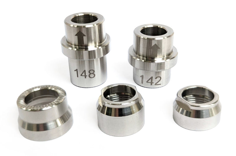 Wahoo KICKR trainer adapter kit showing five silver axle adapters and lock nuts, including 12x142 and 12x148 spacers, on a white background