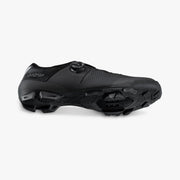 Shimano SH-XC302 cycling shoe in black, tilted to show the side and tread
