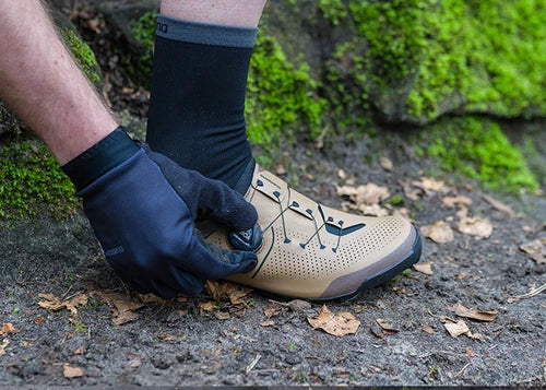 Cyclist adjusting a Shimano SH-XC302 shoe on a forest trail
