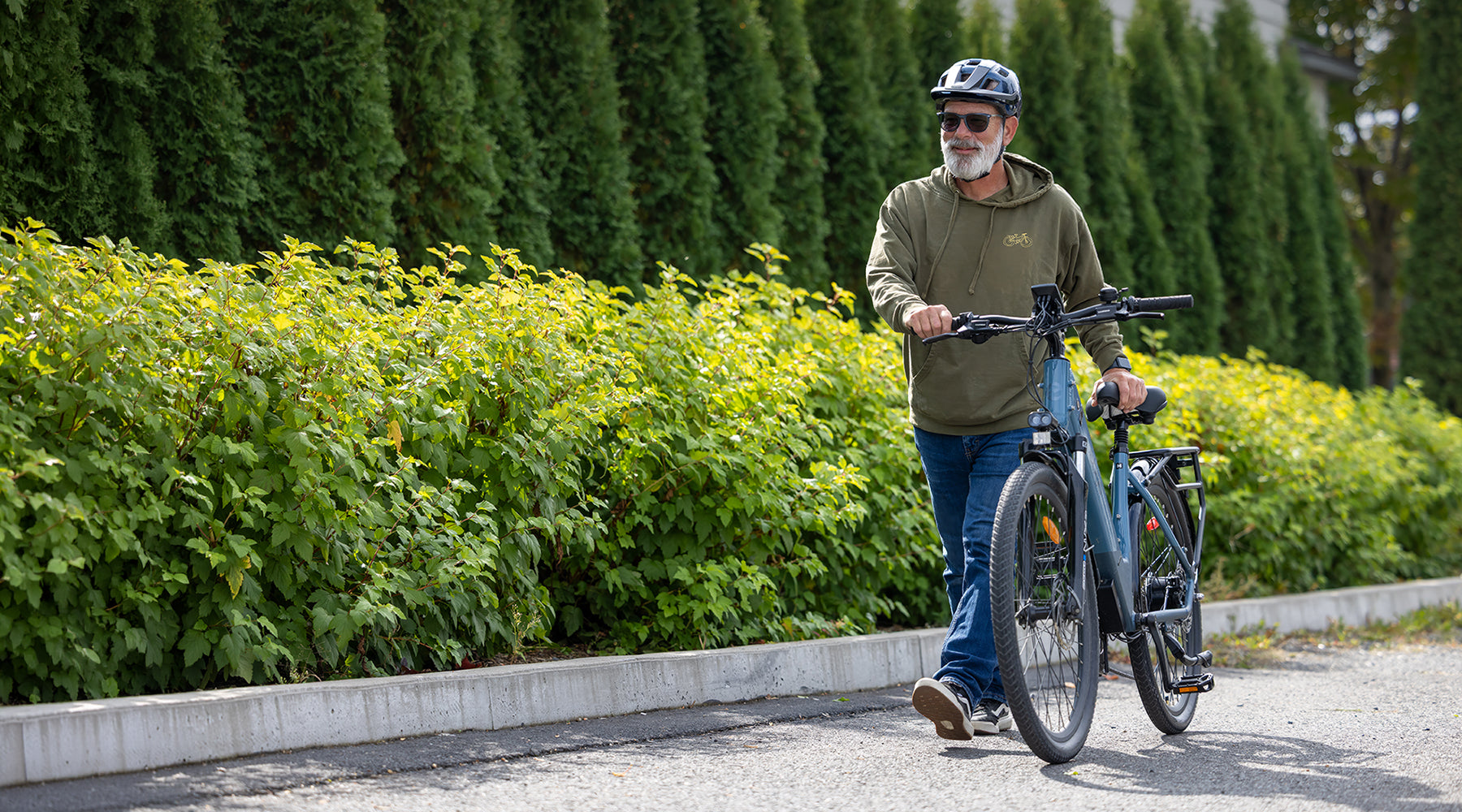Manwalking an electric ebgo bike on a path with greenery in the background