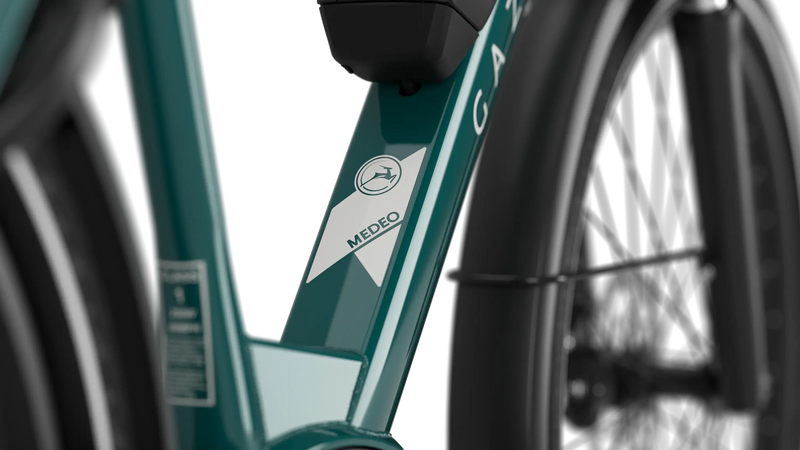 Gazelle Medeo T9 City in Thyme Green Gloss, close-up of top frame tube with 'Medeo' lettering