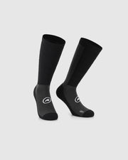 A pair of black and dark gray athletic crew socks with white logo graphics, displayed on a light gray background.