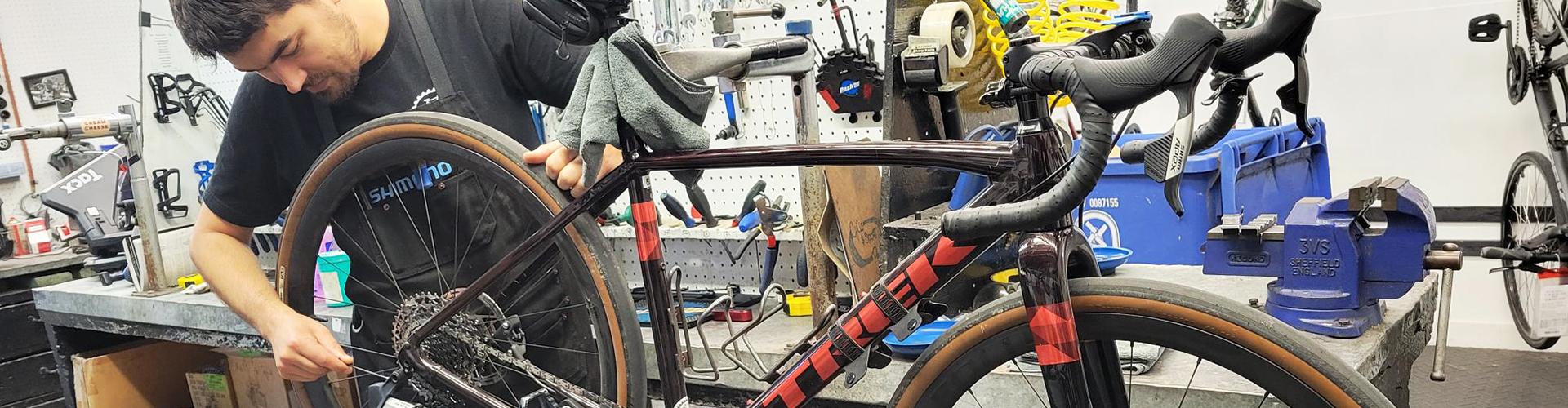 A man in a bike shop tuning up a bicycle.